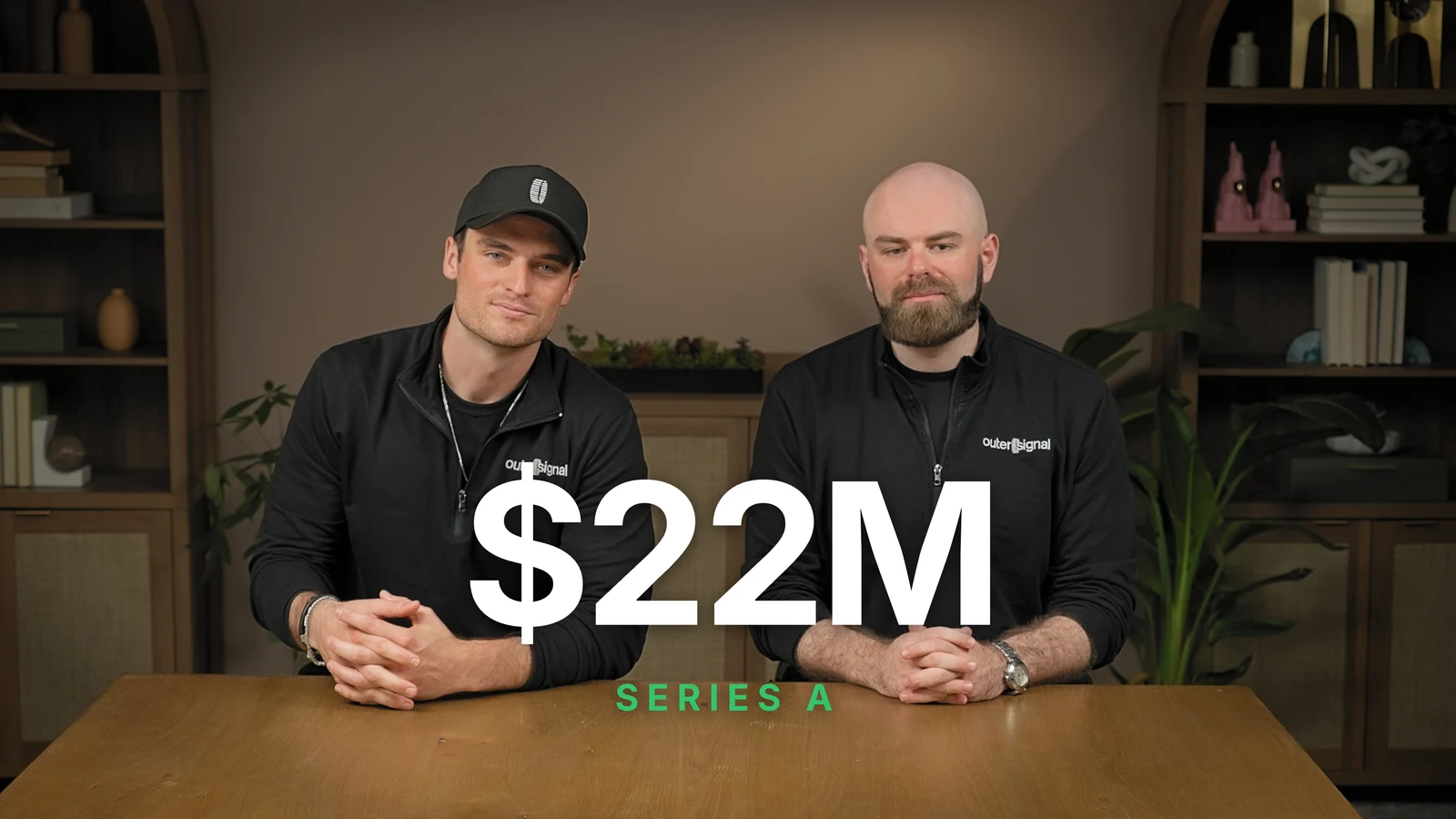 Co-founders Noah and Zach at a table under a large $22M Series A title card