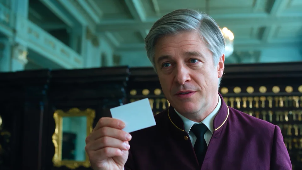 A hotel concierge holds up a blank card